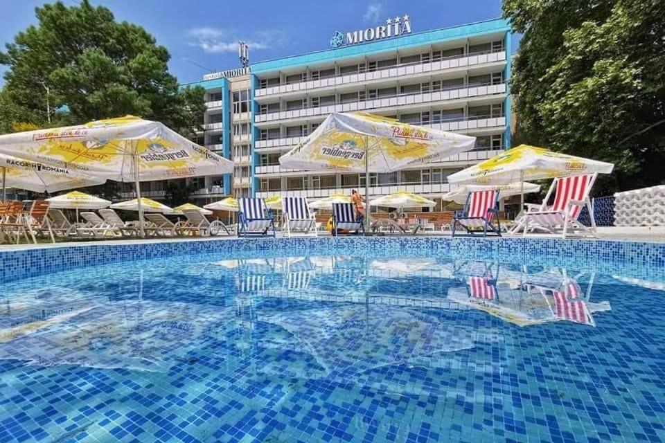a swimming pool with chairs and umbrellas and a hotel at Hotel Miorita Neptun in Neptun
