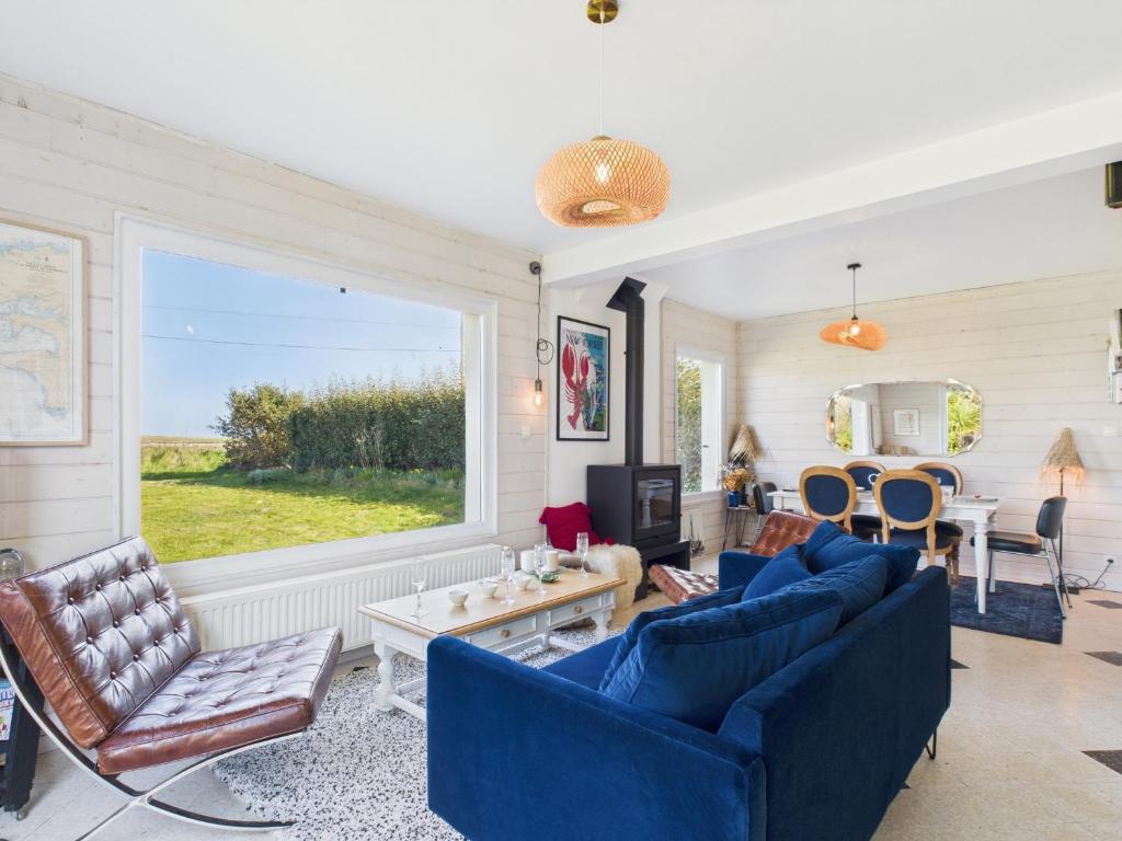 Elle comprend un salon doté d'un mobilier bleu et d'une grande fenêtre. dans l'établissement Ty Gwen Mar - maison les pieds dans l'eau pour 6, à Plouguerneau