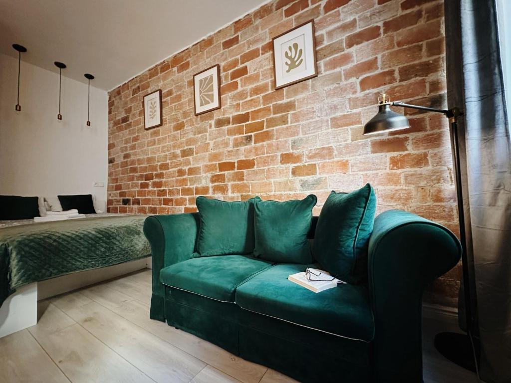 salon z zieloną kanapą i ceglaną ścianą w obiekcie Apartament Egzotyczny w Toruniu