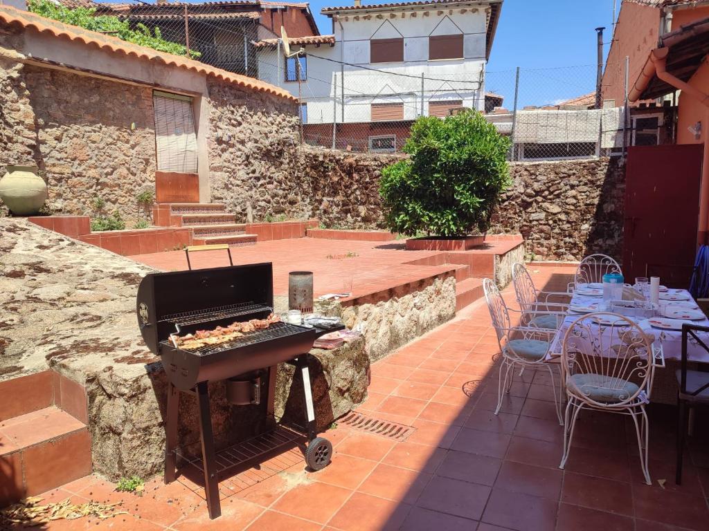 un patio con barbecue, tavolo e sedie di Casa Rogelio Valverde a Valverde de la Vera