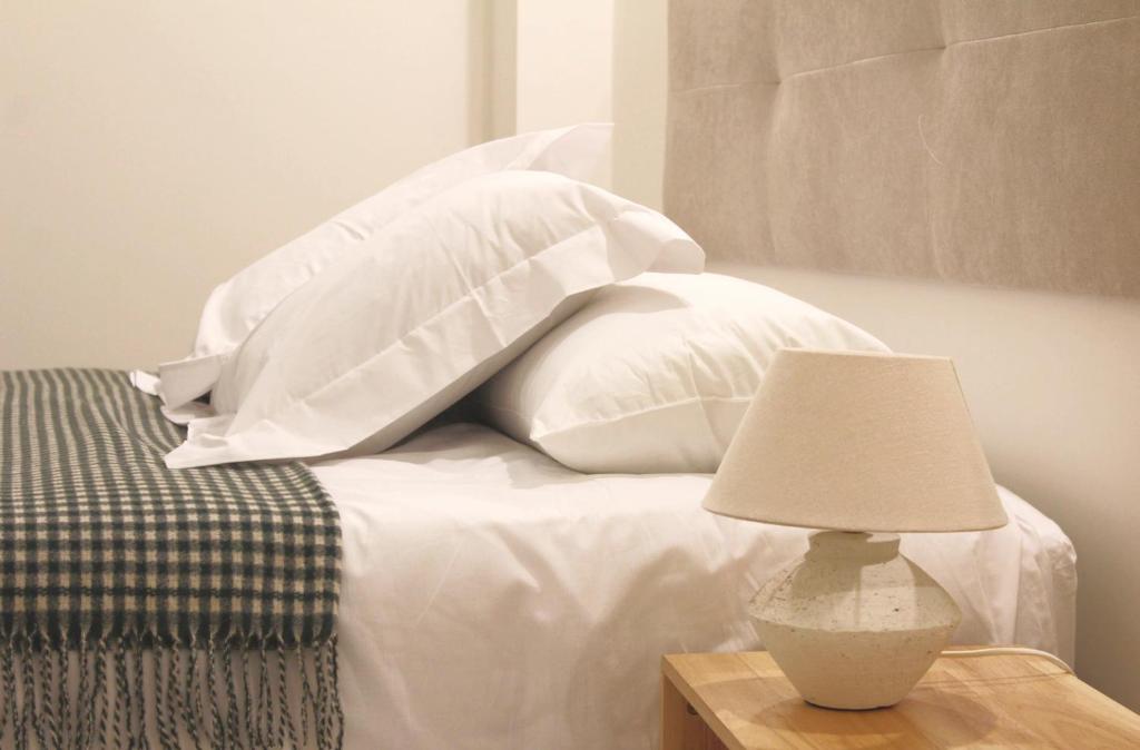 Hotel El Apartamento, a bed with white pillows and a table with a lamp at El Apartamento in Valencia