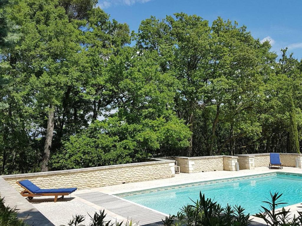 una piscina con una panchina e una sedia blu di Villa Provence élégante climatisée a Oppède