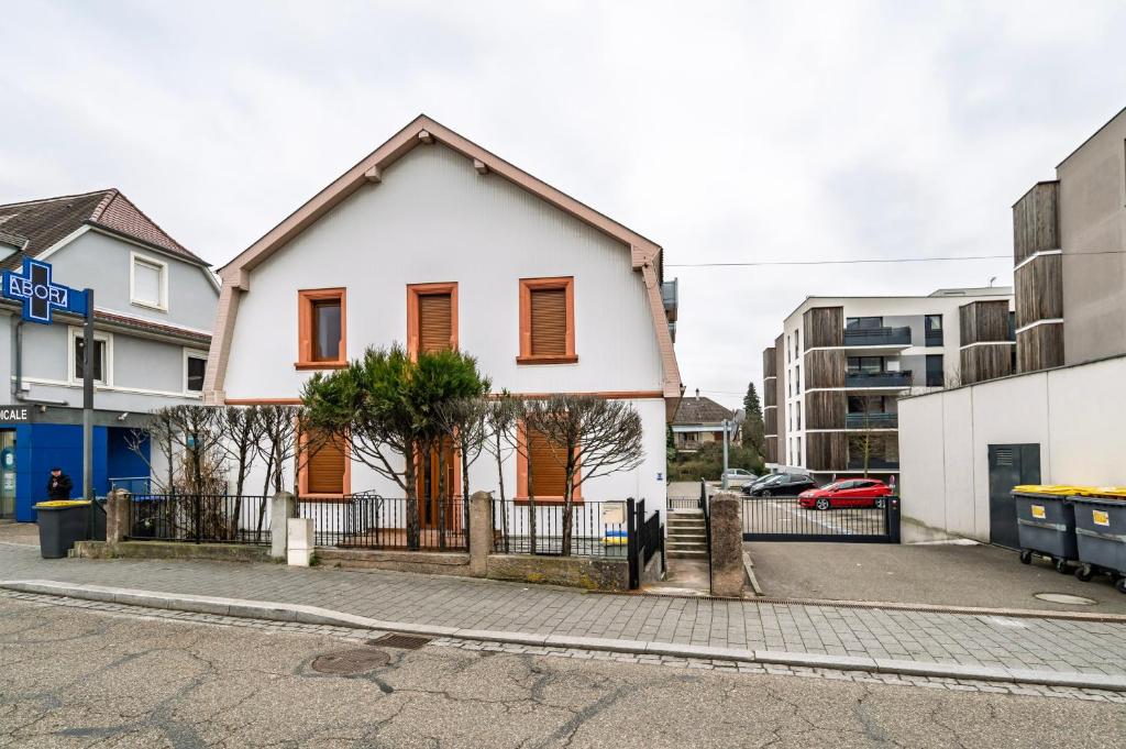 a white house with orange doors on a street at Ostwald - Tram à 4min et 20min du centre de Stras - Confort familial in Ostwald