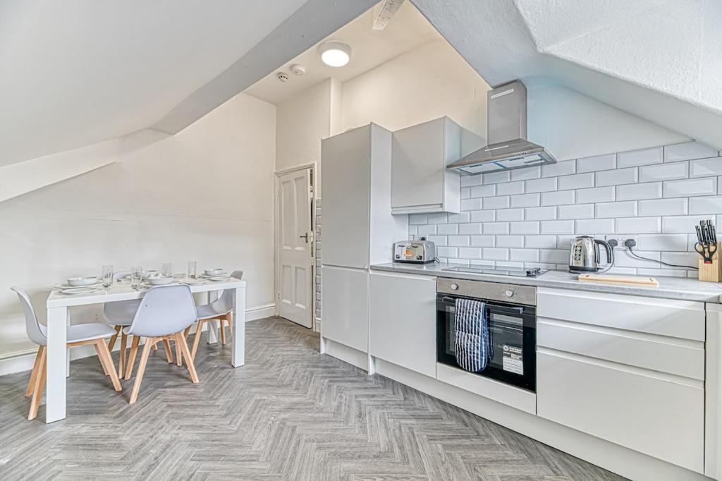una cocina con electrodomésticos blancos, mesa y sillas en Fairhaven View Apartments - Lytham St Annes, en Lytham St Annes