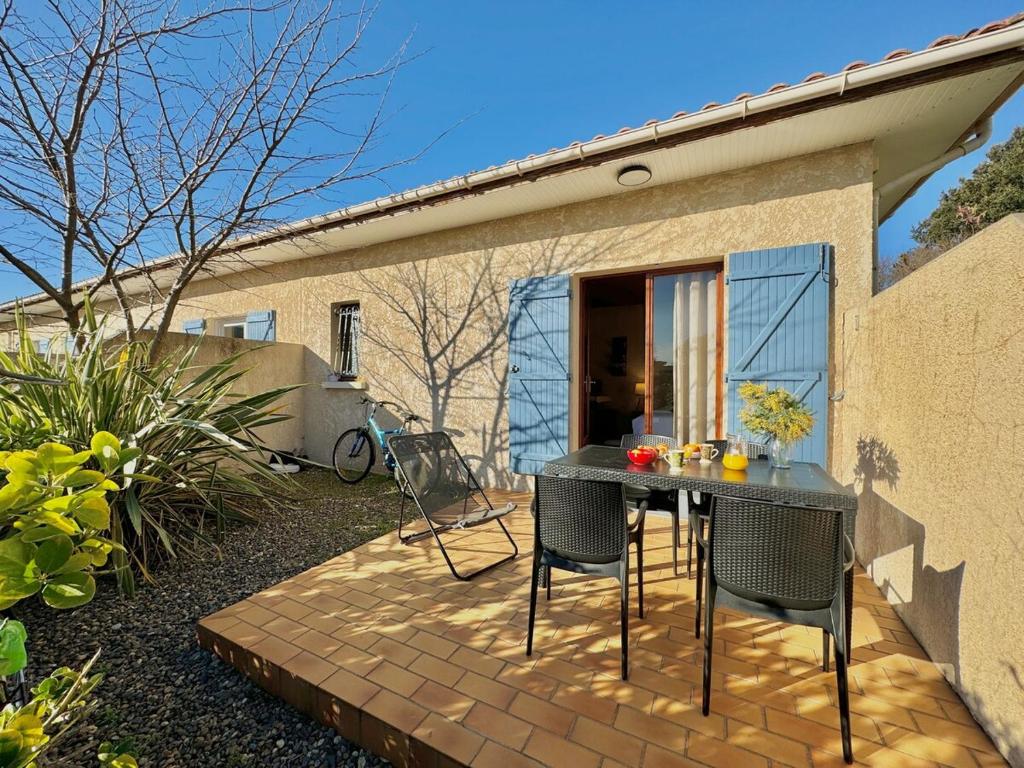 - une table et des chaises sur une terrasse en briques dans l'établissement Rouge Gorge - Studio à 500m des plages, à Mimizan-Plage