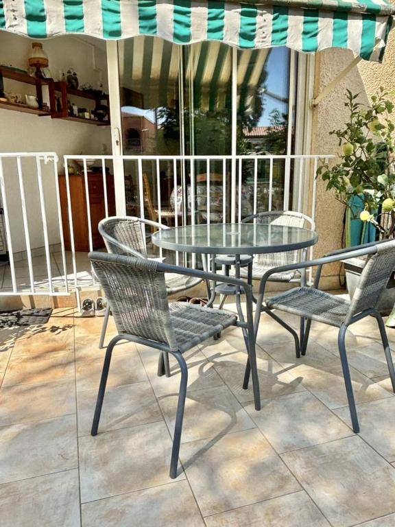 une table et des chaises en verre ainsi qu'un parasol sur la terrasse dans l'établissement STUDIO cabine 2 couchages à LA LONDE LES MAURES LAL110-004, à La Londe-les-Maures