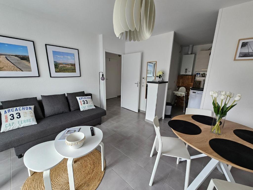 a living room with a couch and a table and chairs at Aux portes des cabanes à huîtres - plage in Lanton