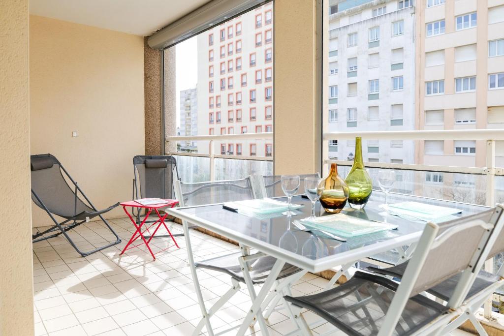une table en verre avec deux bouteilles et des chaises sur un balcon dans l'établissement Appartement emplacement central proche plage - 4 personnes, à Les Sables-dʼOlonne