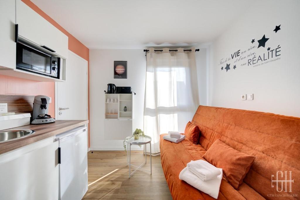 un salon avec un canapé et une cuisine dans l'établissement Jupiter - Proche A10 - 2V - Parking, à Saint-Pierre-des-Corps