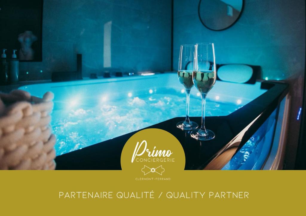 two glasses of wine sitting on a table in a hot tub at FRENCH KlSS - Love Room by PRIM0 C0NCIERGERIE in Clermont-Ferrand