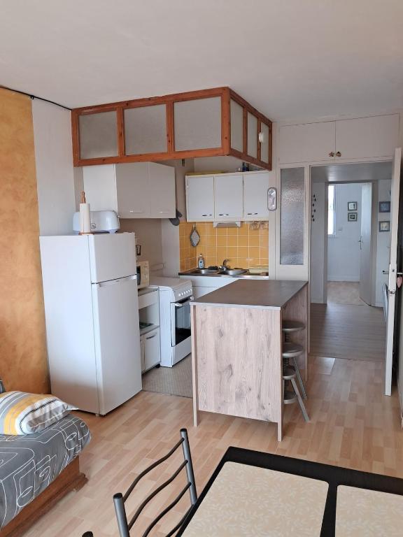 a kitchen with a white refrigerator and a table at Tamaris 42 in Quend-Plage