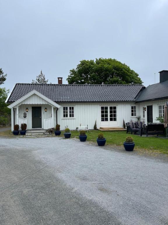 a white house with potted plants in front of it at Recently Refurbished Farm House in Larvik