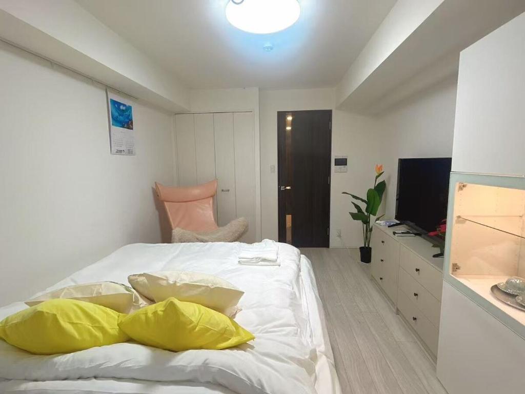 a bedroom with a bed with yellow pillows and a television at ReimiMondo 303 in Tokyo