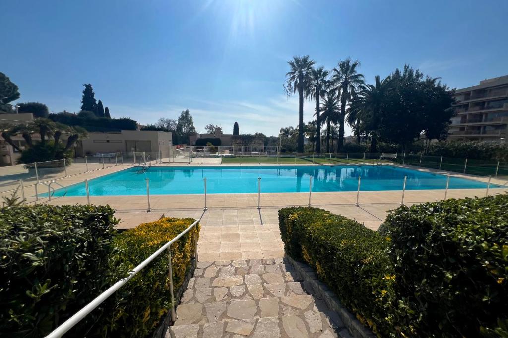 une grande piscine bleue avec des arbres et des buissons dans l'établissement JUAN LES PINS - 4 people - swimming pool - tennis, à Juan-les-Pins