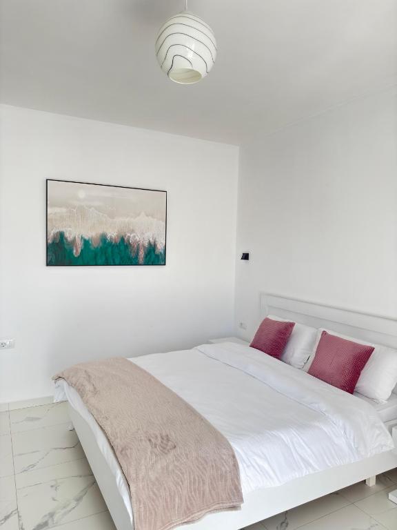 a white bedroom with a white bed with purple pillows at Villa Denis Ksamil in Ksamil