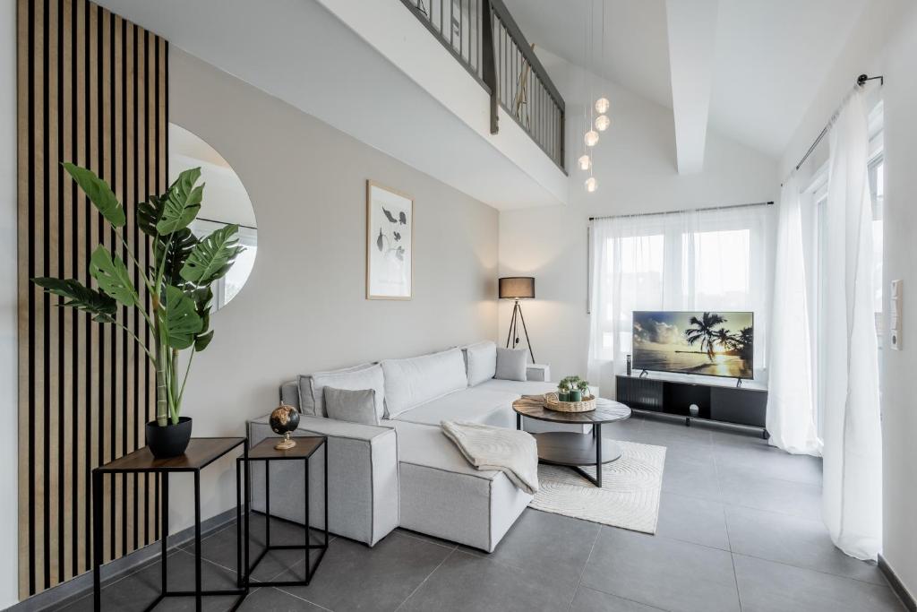 a living room with a white couch and a tv at GT-City Suite 02 I Gasgrill I Smart-TV I Balkon in Gütersloh