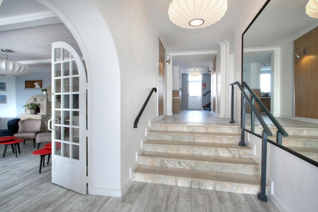 a staircase in a home with white walls and wooden floors at Hôtel La Petite Sirène Quiberon in Quiberon