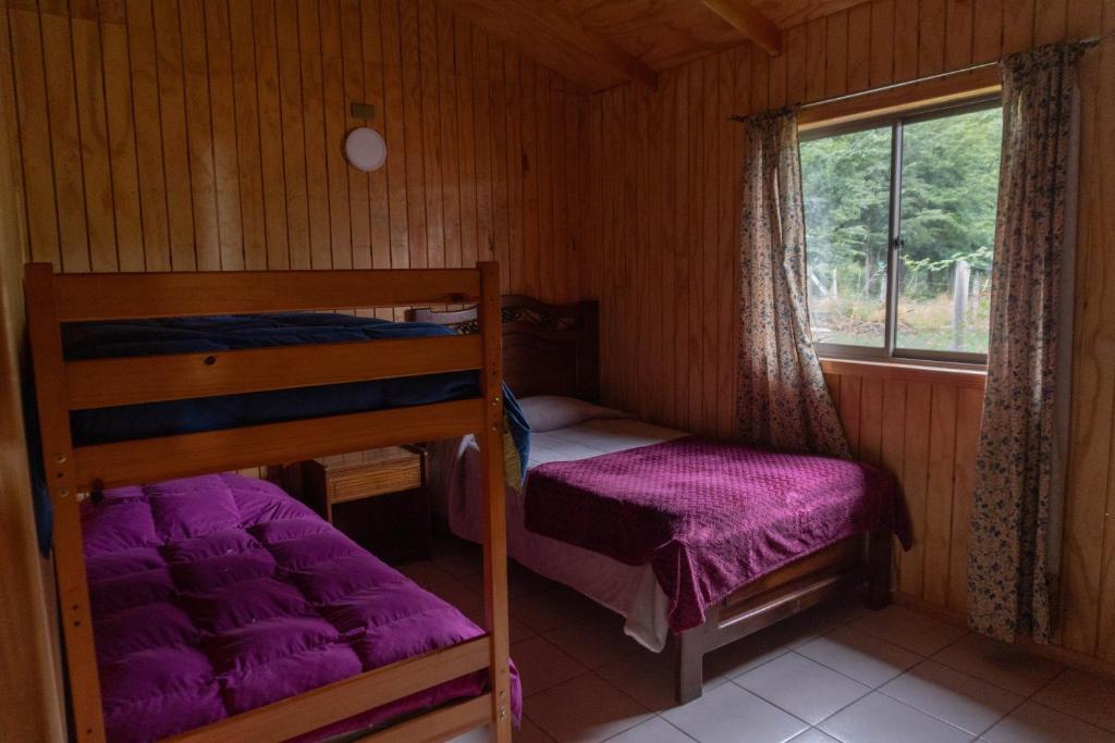 a bedroom with two bunk beds and a window at Cabañas Altos de carewe , Lican Ray chile in Licán Ray