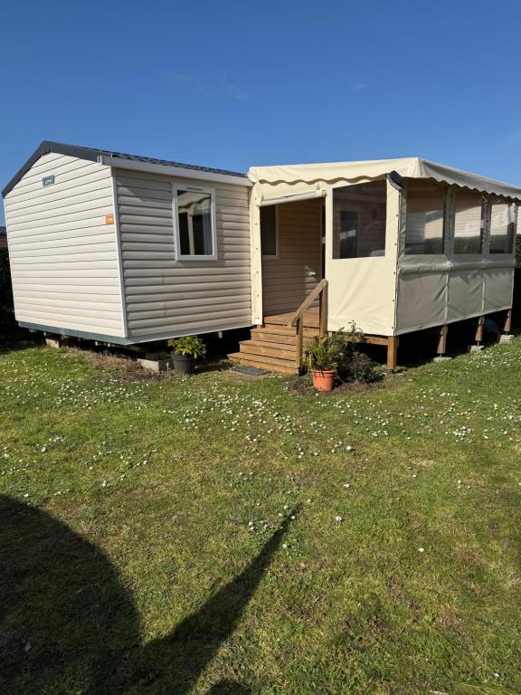 un mobile home avec une terrasse couverte et une maison dans l'établissement Mobile home au calme et paisible, aux Mathes