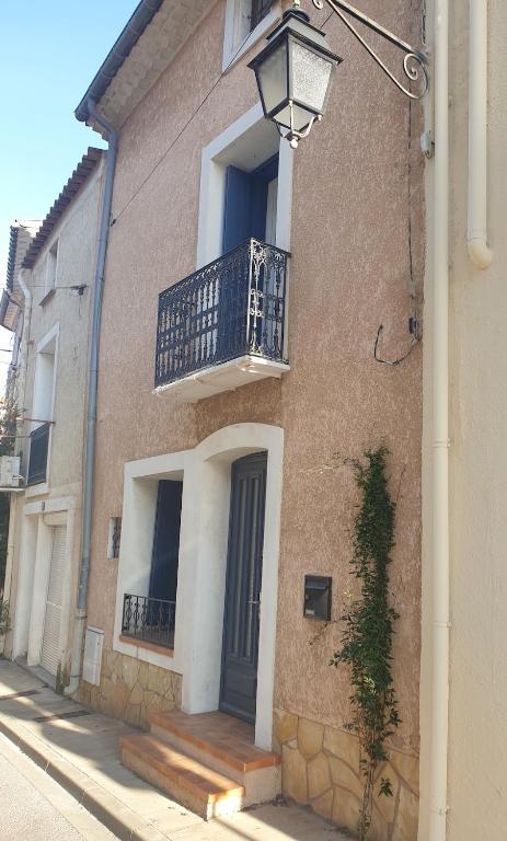 un bâtiment avec une terrasse couverte et un balcon. dans l'établissement Maison de village proche de l'étang et de la mer, à Marseillan