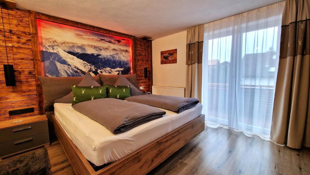 a bedroom with a large bed with a painting on the wall at Ferienwohnung in Pfronten