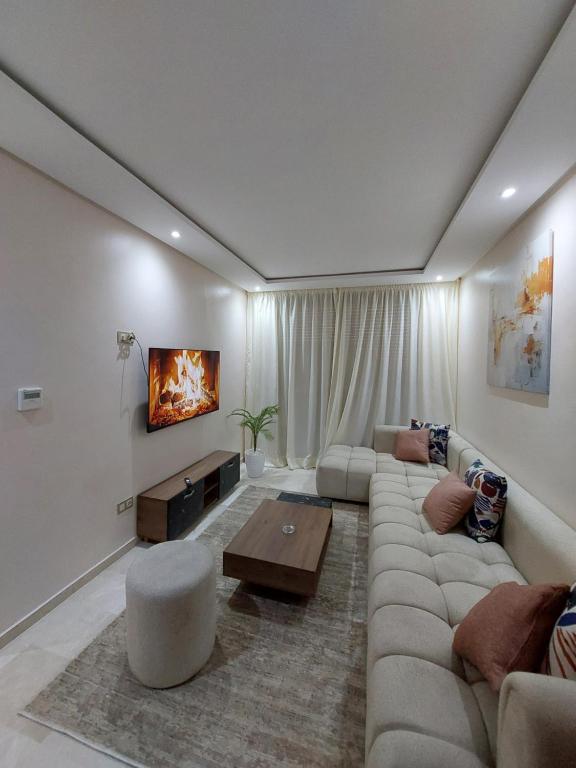 a living room with a large couch and a tv at Appartement centre ville marrakech in Marrakech