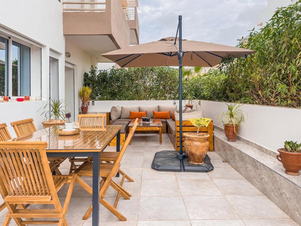 a patio with a table and an umbrella at Secure Luxury Apartment With Swimming Pools in Imi Ouaddar
