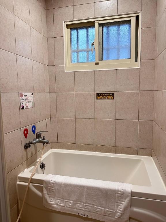 e bagno con finestra e vasca. di 彤林溫泉民宿 a Jiaoxi
