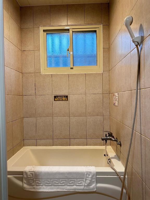 bagno con vasca e finestra di 彤林溫泉民宿 a Jiaoxi