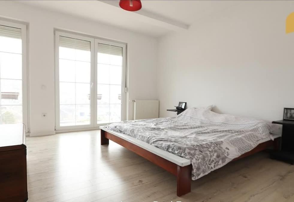 1 dormitorio blanco con 1 cama en una habitación con ventanas en La Casa Hostel, en Pristina