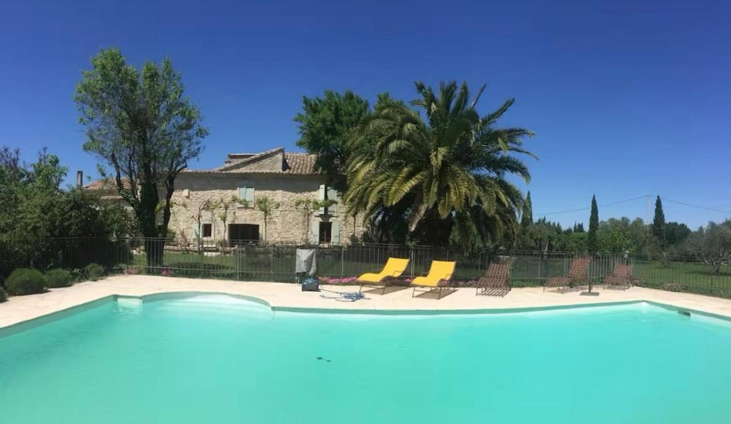 une piscine avec des chaises et une maison en arrière-plan dans l'établissement L'évasion Provencale, à Saze