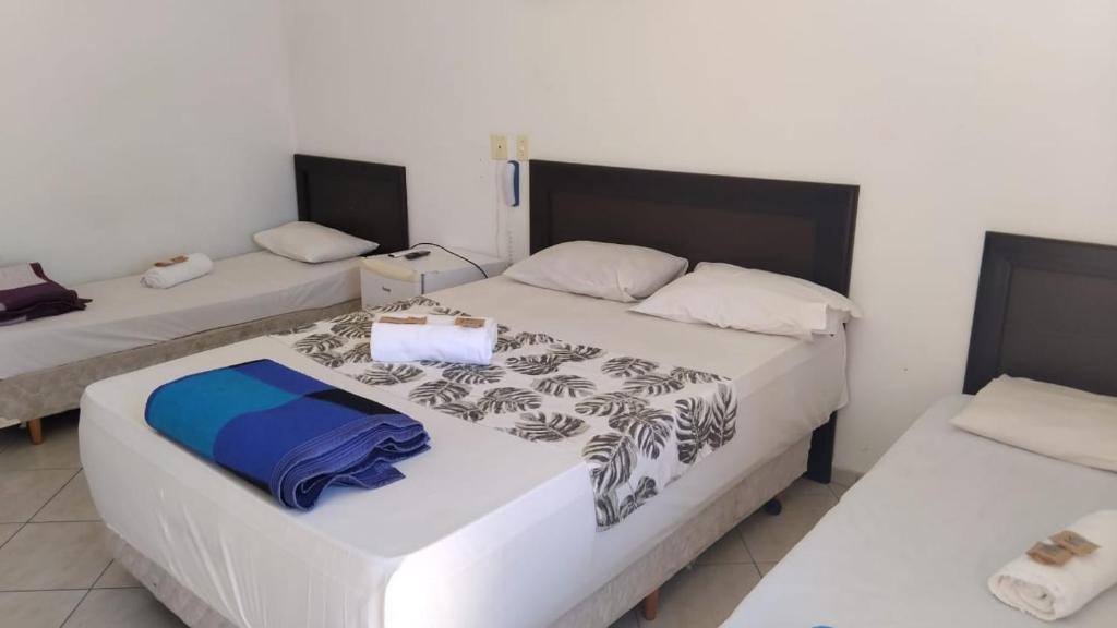 a bedroom with two beds with white walls at Sol do Pernambuco in Guarujá