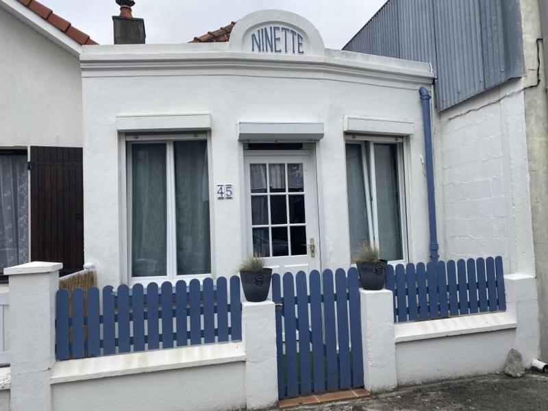 une clôture bleue devant une maison blanche dans l'établissement Ninette, à Fort-Mahon-Plage