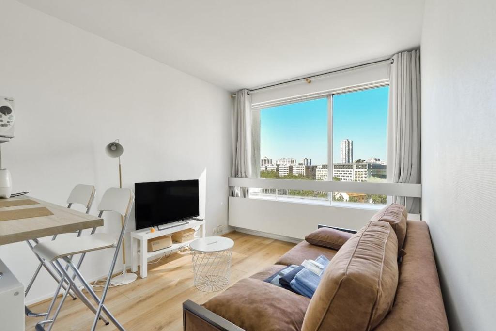 un salon avec un canapé et une grande fenêtre dans l'établissement Beautiful Studio at La Défense near Paris, à Puteaux