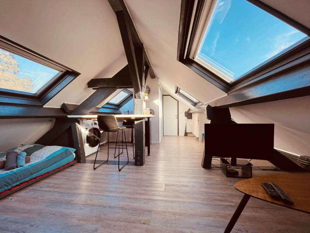 Cette chambre mansardée dispose de lucarnes, d'une table et d'un piano. dans l'établissement Rouen d'en Haut - 373, à Rouen