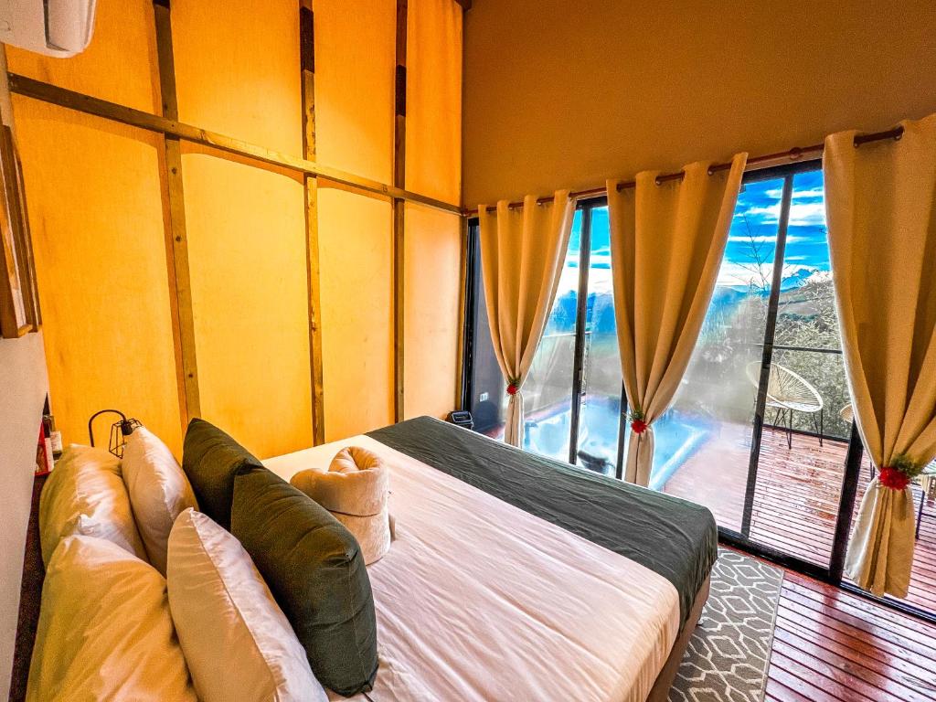 Un dormitorio con una cama y una ventana grande. en Cabañas para parejas cerca a Medellín - LUUM By Roots Rentals, en Marinilla