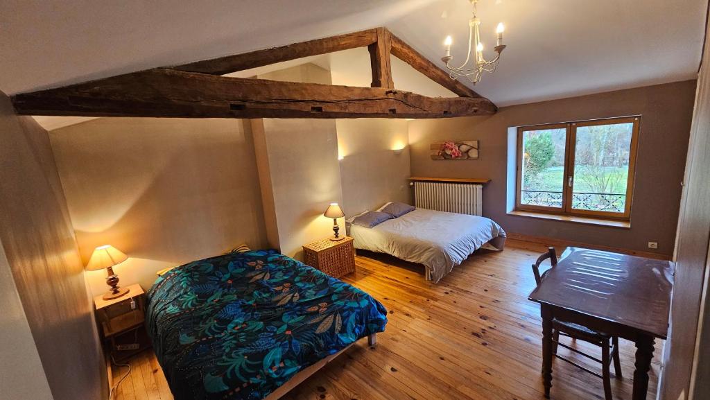 a bedroom with a bed and a desk and a window at Grande maison idéale réunions familiales in Nervieux