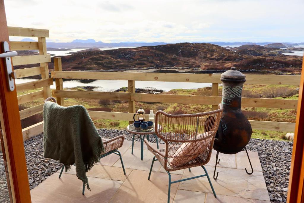 a patio with two chairs and a table with a view at Badcall Bay Retreat in Badcall