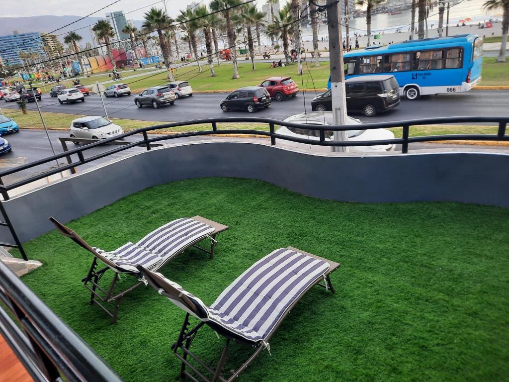 two lawn chairs sitting on a balcony with a street at Hermosa casa frente a cavancha in Iquique