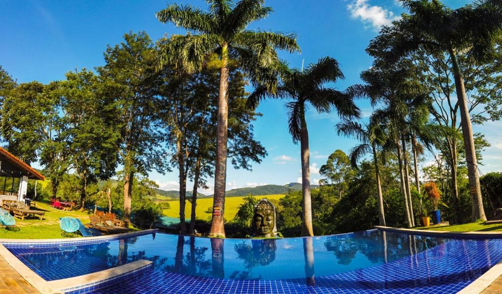 Una piscina de resort con palmeras al fondo en Villa Verde Pousada Gastronômica, en Bom Jesus dos Perdões