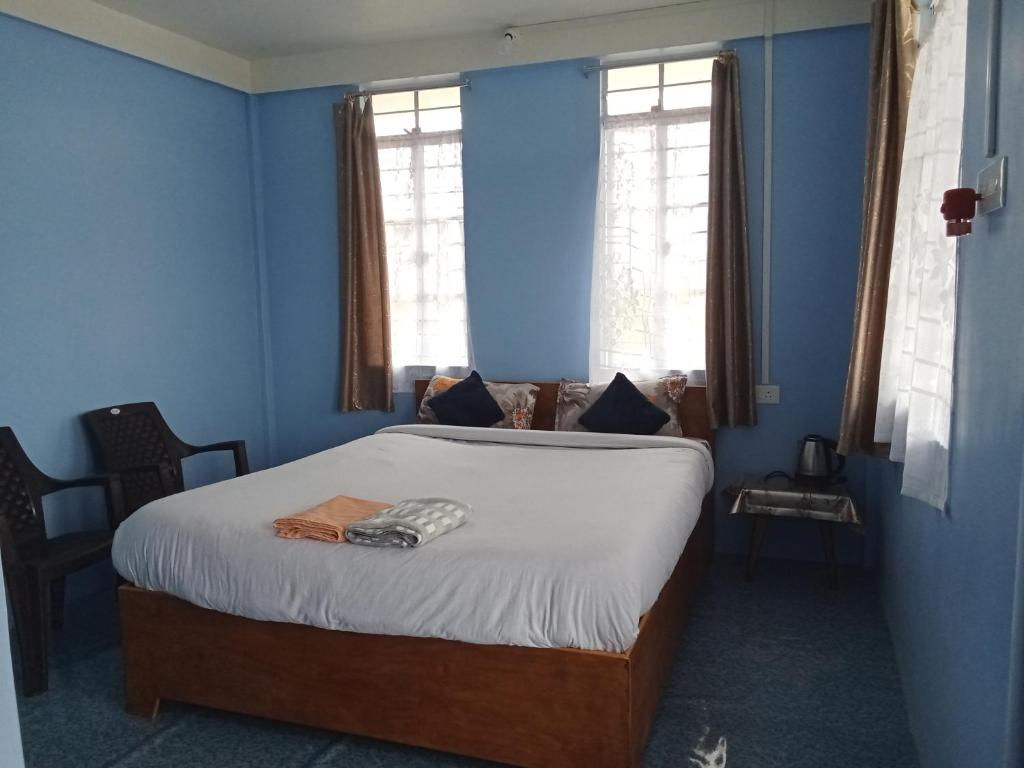 a bedroom with a bed with blue walls and windows at N D Phisha Homestay in Cherrapunji