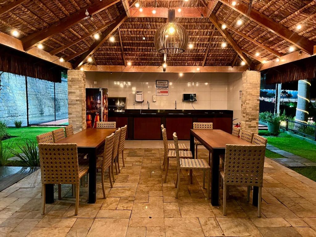 a patio with two tables and chairs and a kitchen at Flat no Condomínio Alto da Serra Villas in Bananeiras