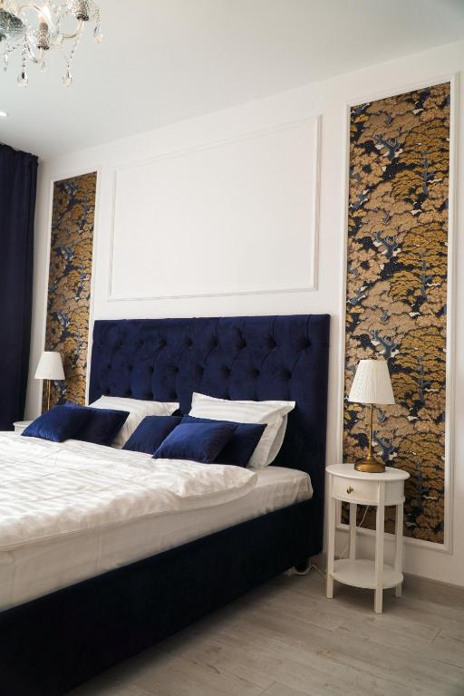 a bedroom with a large bed with a blue headboard at Royal Elegance Apartment in Bucharest
