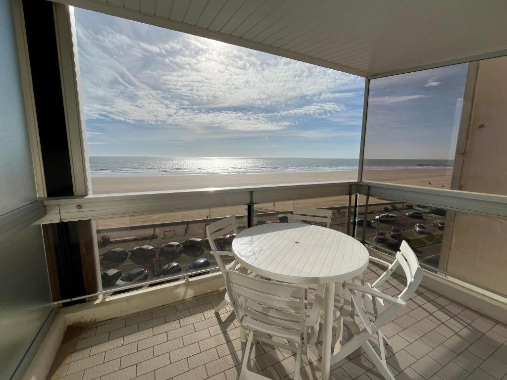 une table et des chaises sur un balcon avec vue sur la plage dans l'établissement La Rochejacquelein, à Saint-Jean-de-Monts