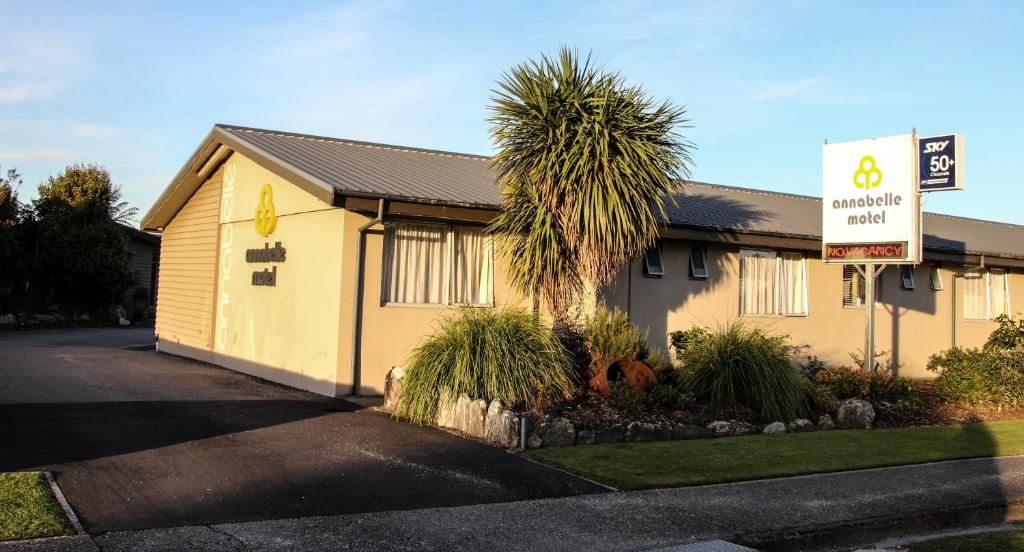 a yellow building with a palm tree in front of it at Annabelle Motel in Hokitika