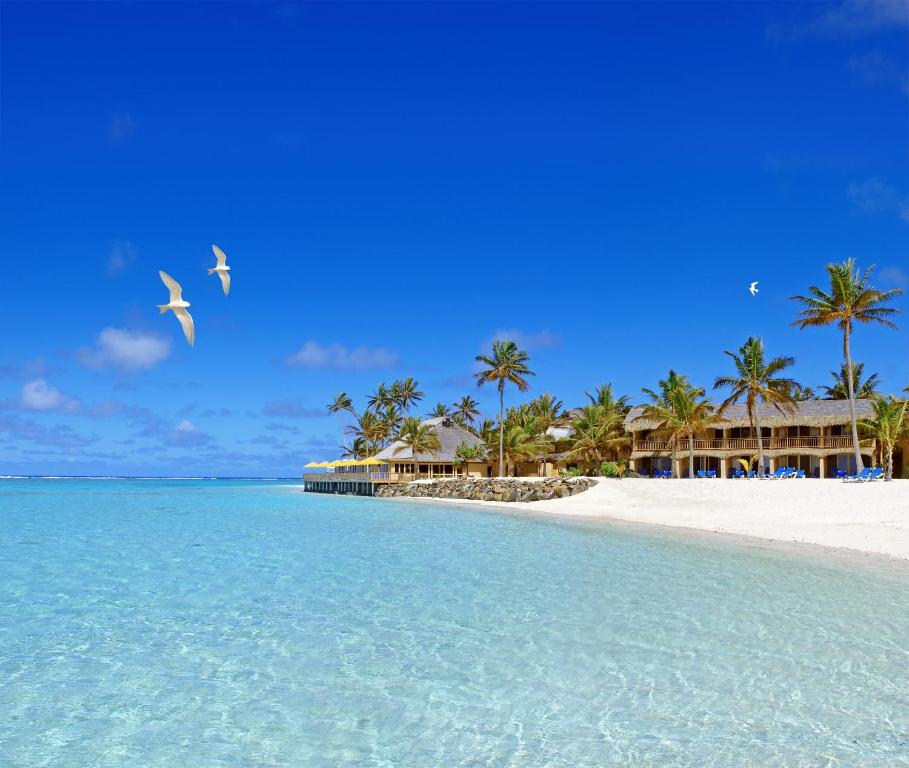 a beach with two birds flying over the water at Sanctuary Rarotonga on the Beach (Adults Only) in Rarotonga