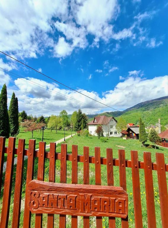 a wooden bench with a sign on a fence at Casa Santa Maria Bran in Moieciu de Jos