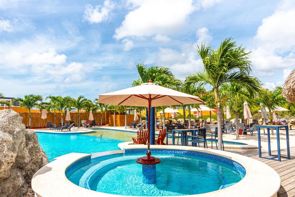 a pool with an umbrella and a table and chairs at The Ritz Village in Willemstad