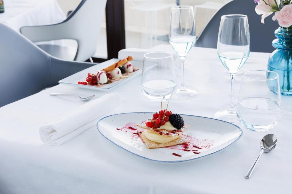 a plate of food on a table with wine glasses at JR Hotels Bari Grande Albergo delle Nazioni in Bari