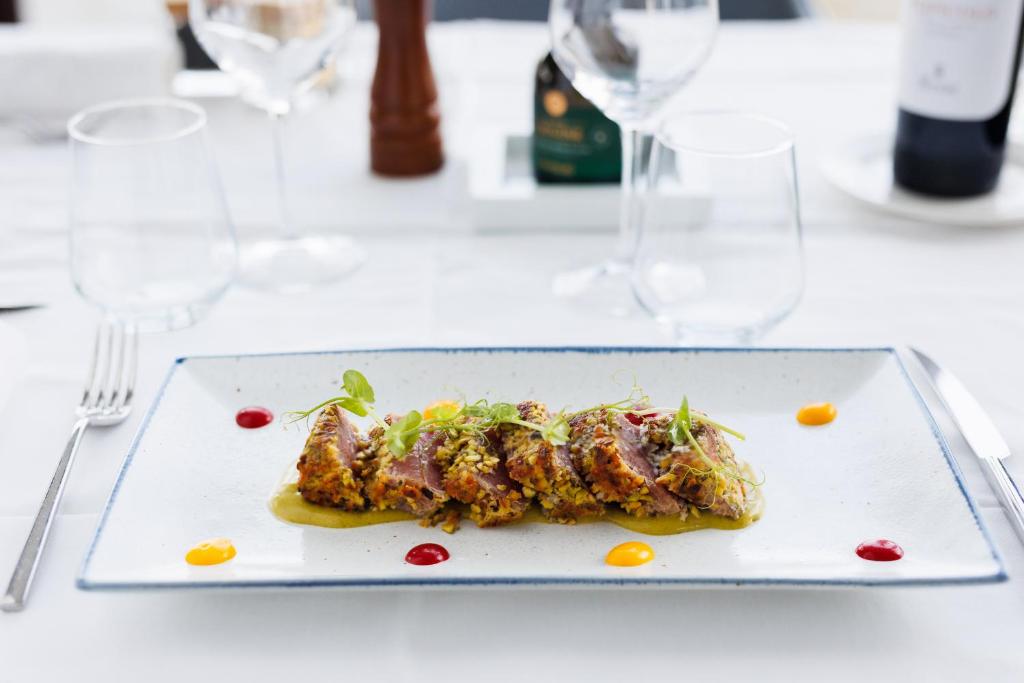a plate of food on a table with wine glasses at JR Hotels Bari Grande Albergo delle Nazioni in Bari